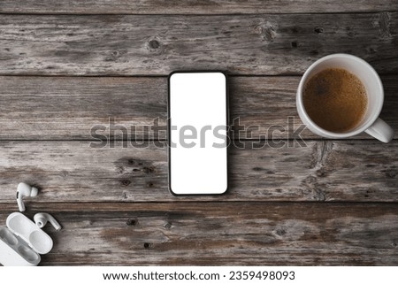 Mobile phone on wooden table showing blank screen, shot from above