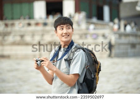 A young man holding a camera and taking pictures during a trip to Korea	
