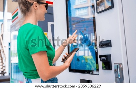 Young woman paying for coffee at vending machine using contactless method of payment  Royalty-Free Stock Photo #2359506229