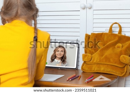 Online courses, classes and education concept. Child looking at tablet gadget with teacher on screen