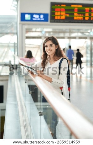 a young foreign woman looking at a map at a train station	
