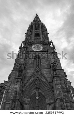 Vertical view of the bell tower of the famous cathedral of Fribourg (Freiburg), Baden Wurttenberg, Germany. Gray dramatic clouds on the background. Monochromatic.