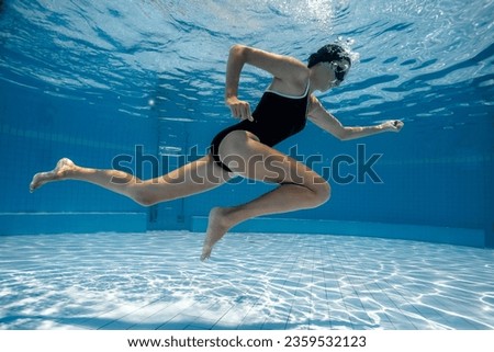 Woman under water runs along the bottom of a swimming pool