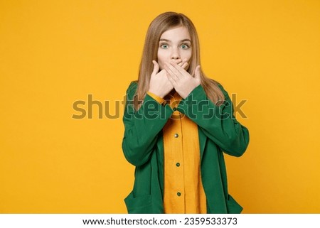 Little blonde kid shocked girl 12-13 years old in casual clothes green shirt cover palms mouth oops gesture isolated on yellow orange background children studio portrait. Childhood lifestyle concept Royalty-Free Stock Photo #2359533373