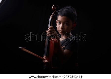 Young boy playing violin on a black background