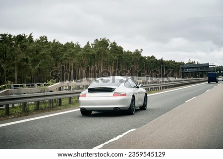 Exquisite Speed and Style on the Highway. Modern European Sportcar. Silver German roadster vehicle on the highway. Silver sport coupe. The expensive sports car on public roads. Autobahn speeding Royalty-Free Stock Photo #2359545129