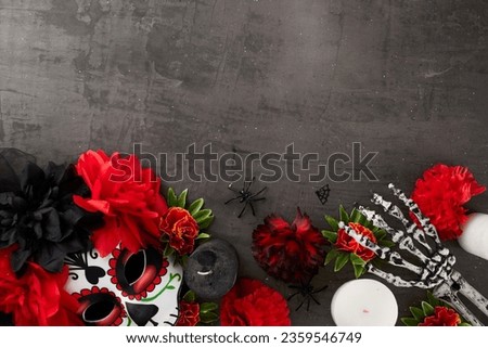 Immerse yourself in the allure of Dia de los Muertos. Top view of traditional mask, beautiful flowers, candles, skeleton arm, creepy decor on texture grey background with ad zone