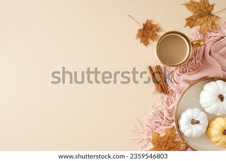 Experience the warmth of home during autumn. Top view photo of cozy cute pleid, hot coffee, pumpkins on the plate, cinnamon sticks, dry autumn leaves on pastel beige background with ad zone