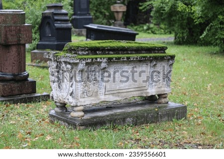 Ancient cemetery gravestone covered with moss Royalty-Free Stock Photo #2359556601