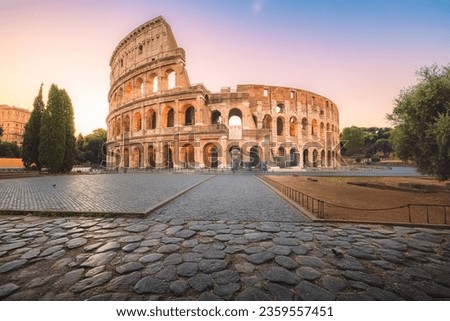 Iconic Flavian Amphitheatre, the ancient Roman Colosseum, a famous tourist landmark, illuminated at sunrise or sunset in historic Rome, Italy. Royalty-Free Stock Photo #2359557451