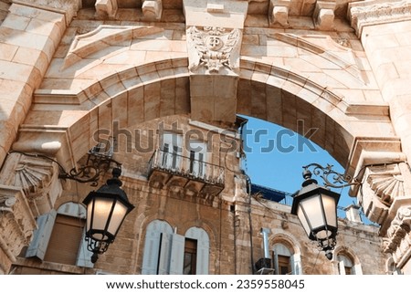Evocative snapshot of two lanterns hanging under an archway, with the timeworn houses of Jerusalem's Old City casting a historical backdrop. Ancient architecture with atmospheric lighting. Royalty-Free Stock Photo #2359558045