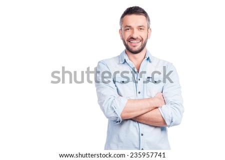 Charming handsome. Handsome young man in casual wear keeping arms crossed and smiling while standing isolated on white background
