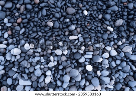 Gray pebbles as a background. Round stones on the beach. Photography for design. Image for background and wallpaper. Textures in nature.