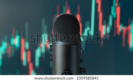 In the foreground, a black microphone. In the background, a blurry stock exchange, red and green candles of share market, podcast about investment, finance audio show.