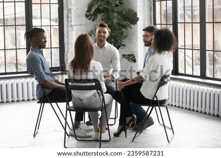 Smiling diverse multiracial colleagues sit in circle participate in motivational teambuilding or training together, multiethnic people take part in psychological session or therapy, give help support Royalty-Free Stock Photo #2359587231