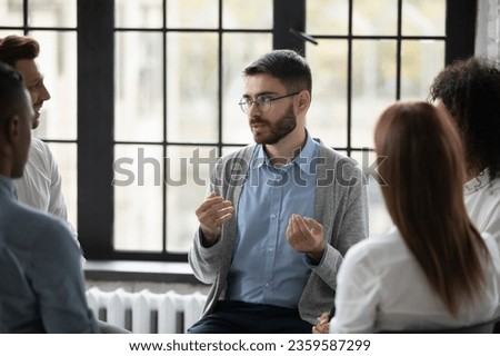 Caucasian male talk share thoughts with diverse people participate in group psychological session together, multiracial friends addicted involved in team mental therapy, give help and support Royalty-Free Stock Photo #2359587299