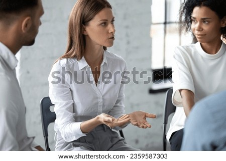 Diverse people sit in circle at business or motivational training talk share thoughts or experiences, multiracial friends colleagues participate in psychological counseling session or therapy in group Royalty-Free Stock Photo #2359587303