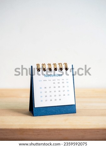 An November 2023 calendar desk for the organizer to plan and reminder isolated on wood table and white background, vertical style. Front view of blue small table calendar with page of the 11th month. Royalty-Free Stock Photo #2359592075