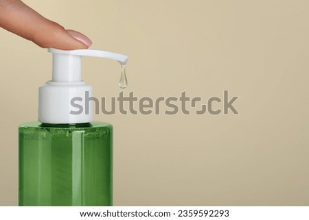 Woman using cleansing gel on beige background, closeup. Space for text Royalty-Free Stock Photo #2359592293
