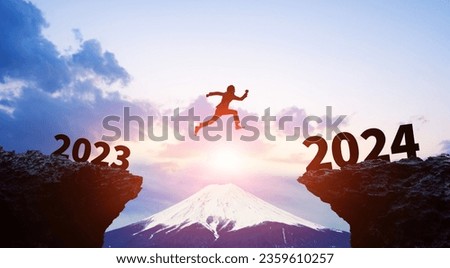 Silhouette of a man jumping from 2023 to 2024. 2024 New Year concept. New year's card 2024. Royalty-Free Stock Photo #2359610257
