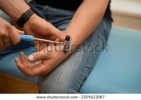 Neurologist checking upper extremity reflex in person during neurological exam