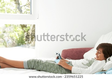 Small happy boy enjoys his last days of vacation, with his tablet, days before going back to school