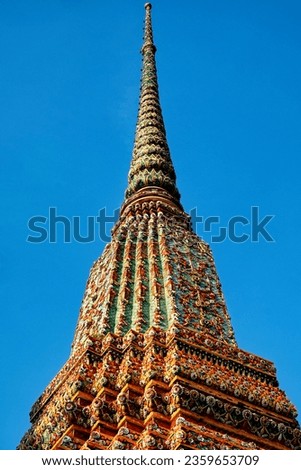 The picture reveals ornate temple spires in Thailand, draped with colorful tiles and patterns, basking in the warm light of the sun.