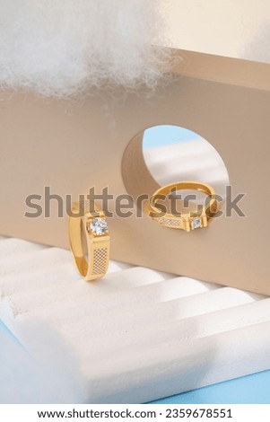 Pair of gold wedding rings with diamonds and matte surface on white textured background. Original design wedding ring bands