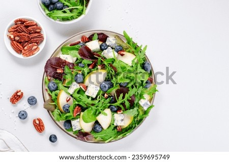 Salad with Pear, Arugula, Blue Cheese, Nuts and Blueberry, Delicious Fresh Salad on Bright Background Royalty-Free Stock Photo #2359695749
