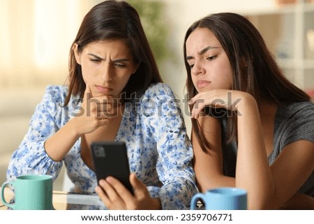 Disappointed women watching media on phone at home Royalty-Free Stock Photo #2359706771