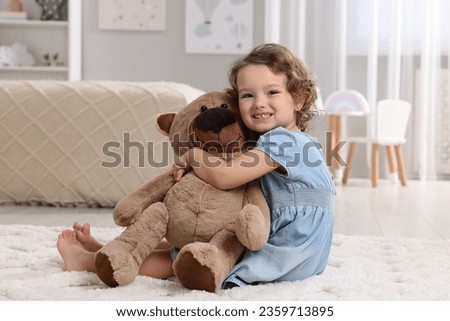 Cute little girl with teddy bear on floor at home Royalty-Free Stock Photo #2359713895