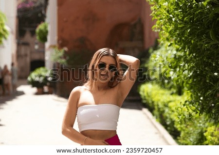 Young and beautiful brunette woman with blonde and latin hair is on holiday in seville. The woman is walking through the Jewish quarter of the Spanish city and poses for pictures making expressions