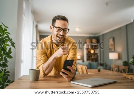 One man adult caucasian male with beard and eyeglasses stand at home happy smile use mobile phone smartphone to make a call talking video call copy space