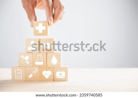 Conceptual image, Hand holds wooden block with healthcare and medical icons. Portrays safety, health, and family well-being, symbolizing pharmacy, heart care, and happiness. health care concept