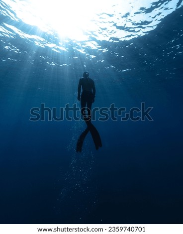 Freediver Swimming in Deep Sea With Sunrays. Young Man DIver Eploring Sea Life. Royalty-Free Stock Photo #2359740701