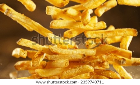 French fries - fried potatoes hitting the table. Fast food meal in freeze motion. Royalty-Free Stock Photo #2359740711