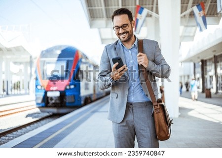 Modern business travel demands modern technology. Confident businessman talking on mobile phone while walking outside the train station with a suitcase. Another success business trip 