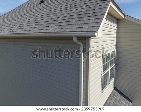 Aerial closeup view gable with vinyl siding, white frame gutter guard system, fascia, drip edge, soffit, on a pitched roof attic at a luxury American single family home neighborhood USA Royalty-Free Stock Photo #2359755909