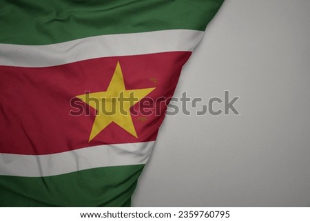 big waving national colorful flag of suriname on the gray background. macro