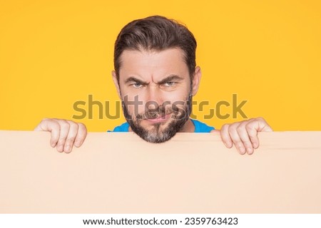 Serious man holds the sign, blank card. Placard ready for your product. Sign to your text. Man showing blank sign board over studio isolated background. Empty blank board. Area for advertising.