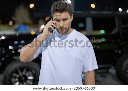 Gangster call phone. Angry man chatting on phone near car on night urban street. Dangerous aggressive man with phone. Criminal city. Danger american district. Aggressive angry man talking on phone Royalty-Free Stock Photo #2359766539