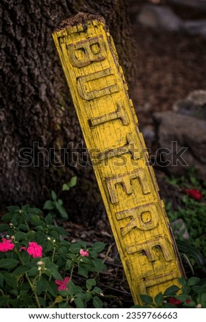 yellow garden sign placed in flower bed