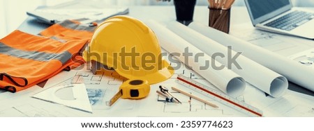 Architectural designed building blueprint layout and engineer tool for designing blueprint with contractor project document on engineer workspace table in office with safety helmet or hardhat. Insight Royalty-Free Stock Photo #2359774623