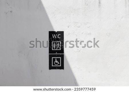 picture of a sign for a toilet, for women and men and the disabled, on a house wall