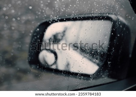 Traveling on a rainy day. Highway reflection in a car mirror