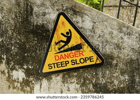 A picture of warning sign of danger steep slope at the wall.