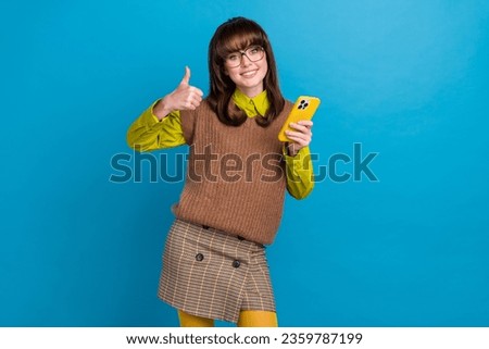 Photo of funky charming woman dressed knitted waistcoat eyewear thumb up communicating modern device isolated blue color background