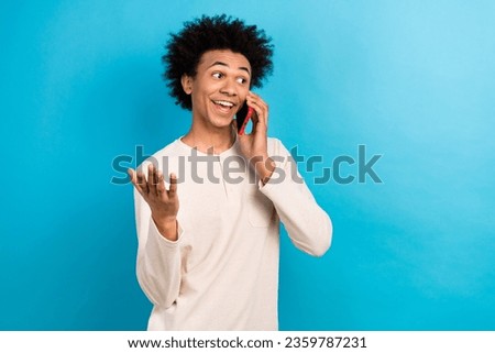 Photo portrait of attractive young man talking phone communicate wear trendy white pajama clothes isolated on blue color background