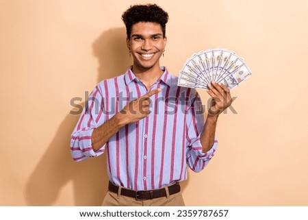 Photo portrait of nice young guy hold point money cash fan wear trendy striped formalwear garment isolated on beige color background