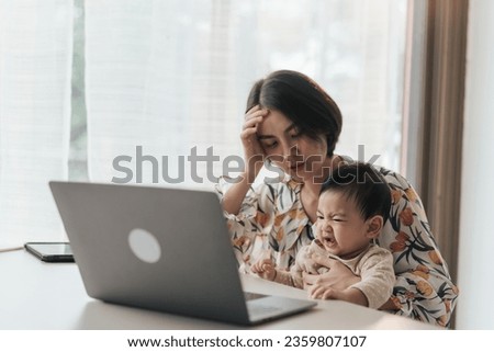 Asian mother are stressed work from home and raising their children.  A little boy Asian baby is disturbing his mother while she is working at home. Concept problem of working from home. Royalty-Free Stock Photo #2359807107
